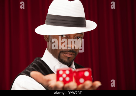 gut gekleidete Spieler in einem Retro-Anzug hält über mittelgroße Würfel Stockfoto