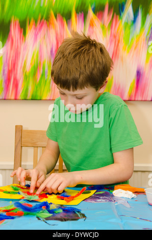 acht Jahre alter Junge Kunst und Handwerk Montage mit Klebstoff Schere und Farbe zu tun. Stockfoto