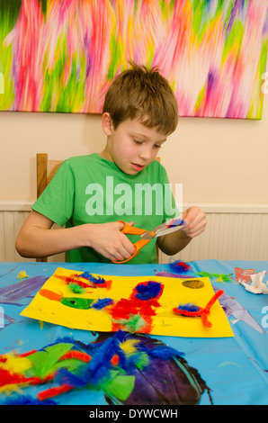 acht Jahre alter Junge Kunst und Handwerk Montage mit Klebstoff Schere und Farbe zu tun. Stockfoto