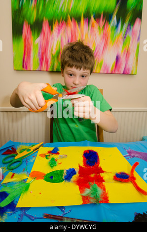 acht Jahre alter Junge Kunst und Handwerk Montage mit Klebstoff Schere und Farbe zu tun. Stockfoto