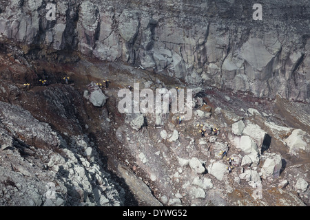 Männer tragen Körbe beladen mit Blöcken von Schwefel, Kawah Ijen, Banyuwangi Regency, Ost-Java, Indonesien Stockfoto