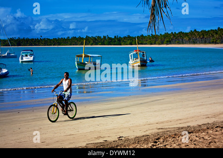 Ein Mann reitet auf seinem Fahrrad am Strand. Tinhare Insel, Bahia, Brasilien Stockfoto