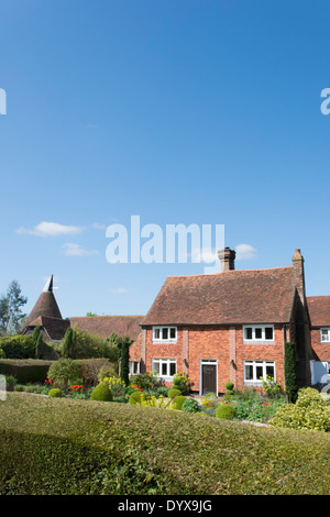 Eine schöne Berghütte in Lamberhurst Kent mit Frühling Tulpen im Garten und Seeregenpfeifer Oast House im Hintergrund Stockfoto