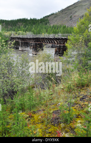 Trübe Landschaft auf einer Route Yakutsk - Magadan. Russland. Holzbrücke in Jakutien über den Bergfluss. Stockfoto