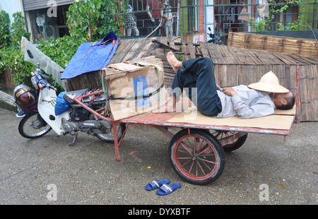 Mann schläft auf Anhänger befestigt, Motorrad in Bat Trang Dorf in der Nähe von Hanoi, Vietnam Stockfoto