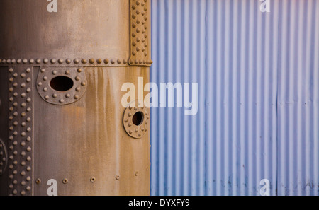 Eine genietete Eisen gerundet aus neben einer Wellblech-Blatt-Wand Stockfoto