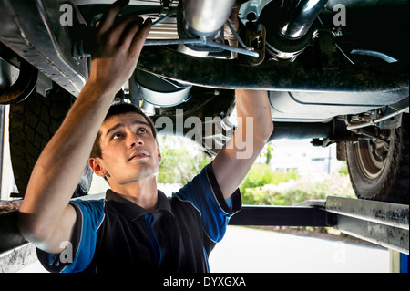 Junge Mechaniker arbeiten unter dem Auto Stockfoto