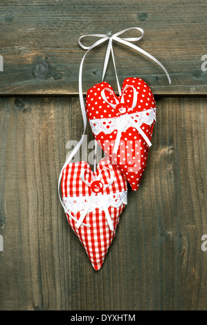 zwei rote Herzen hängen über hölzerne Hintergrund. romantische Valentinstag-Konzept Stockfoto