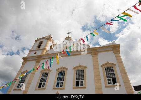 Itaparica Island, Bundesstaat Bahia, Brasilien. Itaparica-Stadt. Restaurierte Kolonialzeit Barockkirche, bunte Girlande. Blauer Himmel und weiße Wolken. Stockfoto