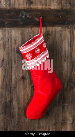 roten Weihnachtssocke mit Schneeflocken für Santa Geschenke aus Holz Hintergrund hängen. Ferien-Symbol-Strumpf Stockfoto