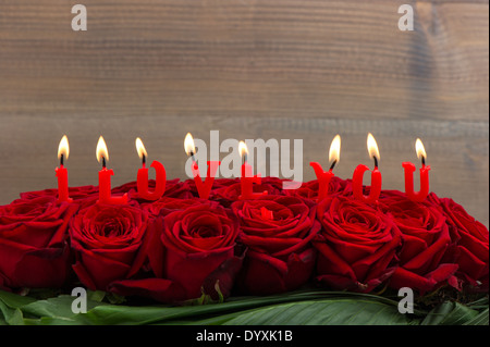 rote Rosen und brennenden Kerzen machen ich liebe dich. Festliche Blumenarrangement. selektiven Fokus Stockfoto