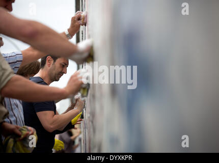 Berlin, Deutschland. 27. April 2014. Menschen reinigen Graffiti Gemälde in der East Side Gallery in Berlin, Deutschland, 27. April 2014. Künstlergruppe Menschen und Touristen zur Reinigung des 1,3 km langen Abschnitts der Berliner Mauer in der Nähe von Berlin-Mitte. Foto: KAY NIETFELD/Dpa/Alamy Live News Stockfoto