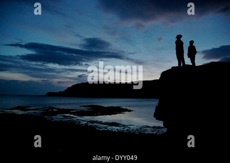 Zwei jungen stehen auf großen Felsbrocken Silhouette Abendlicht, Calgary Bucht in der Abenddämmerung, Isle of Mull, Argyle, Hebriden, Schottland Stockfoto