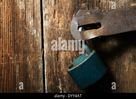 Nahaufnahme eines Vorhängeschlosses und altes Metall Hasp und Heften auf einer alten Holztür Stockfoto