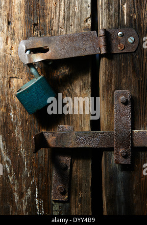 Nahaufnahme eines Vorhängeschlosses und altes Metall Hasp und Heften auf einer alten Holztür Stockfoto