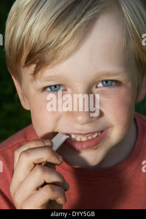 Porträt des Kindes Blond Boy Stretching Bubble Gum vom Mund Stockfoto