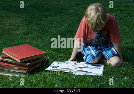 Nettes Kind blonde junge Gras liegend ein Buch lesen Stockfoto