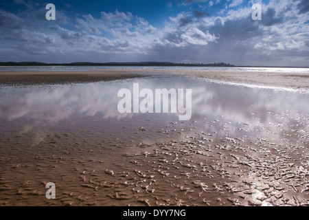 niedrigen Winkel Blick über Wattflächen am Rande Strand mit sanften Welle, fernen Hügel und Meer. sonnigen blauen Himmel Tag Australien Stockfoto