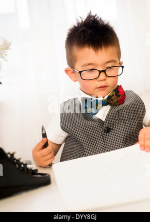 Männliches Kind spielt wie ein Geschäftsmann an seinem Schreibtisch Stockfoto