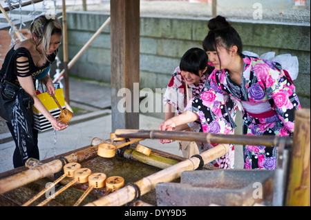 Zwei asiatische Teens tragen traditionelle Kimonos an eine buddhistische Reinigung Brunnen in Kyoto Stockfoto