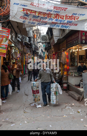 Neu-Delhi, Indien. Schmale Straße auf dem Markt, Chandni Chowk Bereich. Devanagari-Skript auf dem Overhead Banner. Stockfoto