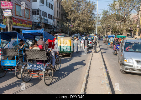 Neu-Delhi, Indien. Rikscha und Pkw-Verkehr auf einer Straße der Innenstadt in Delhi. Stockfoto