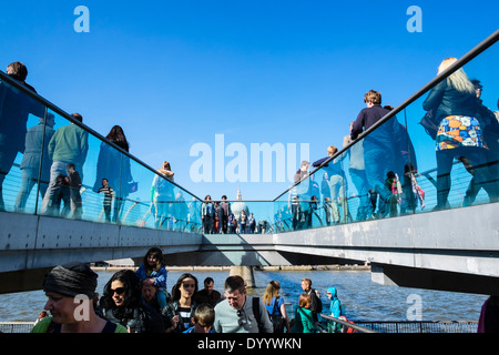 Viele Fußgänger zu Fuß über die Millennium Bridge über die Themse in London Vereinigtes Königreich Stockfoto