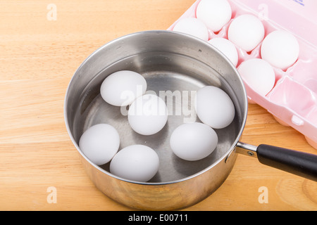 Sechs Eiern in einem Topf Wasser mit sechs weitere in einem Eierkarton Stockfoto