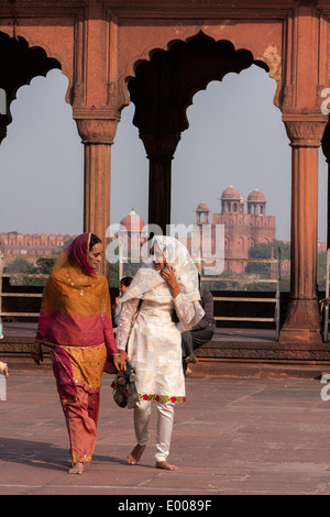 Neu-Delhi, Indien. Muslimische indische Frauen gehen in den Innenhof der Jama Masjid (Freitagsmoschee). Rotes Fort in den Hintergrund. Stockfoto