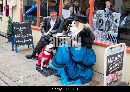 Ein Mann und Frau Partner im Gothic Kleid mit ihrem Bullterrier Hund sitzt an einem Cafétisch bei Whitby Gothic Weekend Frühjahr 2014 Stockfoto