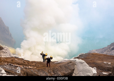 Männer tragen Körbe beladen mit Blöcken von Schwefel, Kawah Ijen, Banyuwangi Regency, Ost-Java, Indonesien Stockfoto