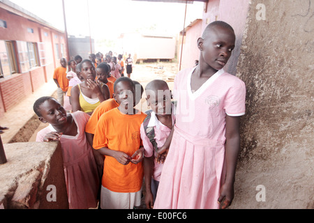 Schülerinnen und Schüler Line-up für ihr Mittagessen bei der NGO finanziert gehütet Kinder Grundschule in den Kosovo Slumviertel von Kampala Stadt Stockfoto