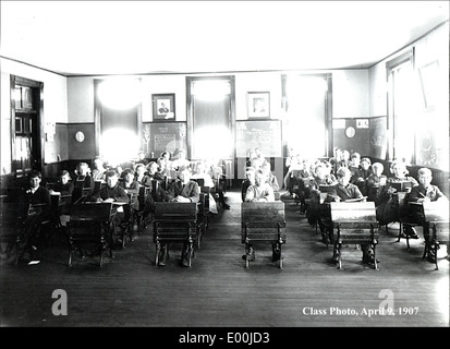 Dieses Foto zeigt eine Klassenszene in Keene, New Hampshire, mit Schülern, die an Schreibtischen sitzen. Das Bild bietet einen Einblick in die schulische Umgebung der Epoche, wobei der Schwerpunkt auf der Interaktion der Schüler und dem Klassenzimmer liegt. Stockfoto