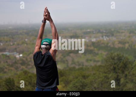 Fit ältere afroamerikanischen Mann hoch über einer Stadt unten dehnen Stockfoto