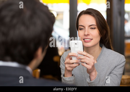 Weiblich männlich fröhlich Smartphone Abendessen bar Sms SMS Surfen web Stockfoto