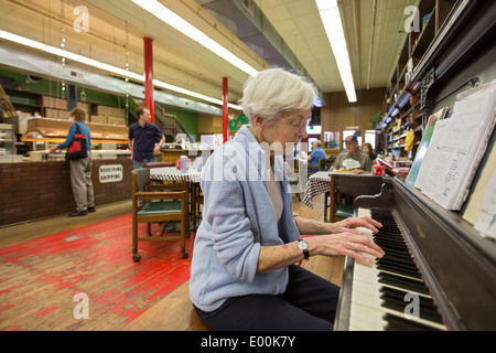 83 Jahre alte Frau spielt Klavier im Pizza-Restaurant Stockfoto