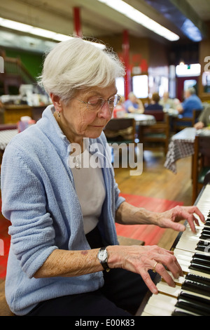 83 Jahre alte Frau spielt Klavier im Pizza-Restaurant Stockfoto