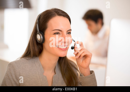 lächelnde weibliche hübsche Schreibtisch Kopfhörer Porträt Stockfoto