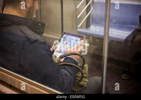 Ein u-Bahn-Fahrer spielt das beliebte mobile Spiel Candy Crush Saga auf seinem iPad in New York Stockfoto