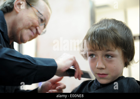 9 Jahre alten Schüler, die einen Haarschnitt in Barbiere in Great Ayton, North Yorkshire, England uk Stockfoto