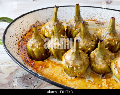 Karamellisierte Artischocken gebacken mit Honig, Sojasauce und Leinsamen auf einem rustikalen Holztisch. Stockfoto