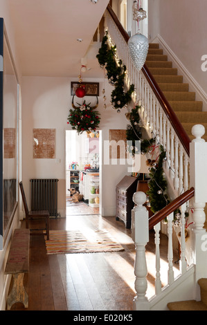 Weihnachtsschmuck hing von einer Treppe in einem Flur mit Holzdielen und verzweifelt suchen Bank