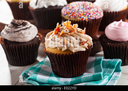 Ausgefallene Gourmet Muffins mit Zuckerguss auf einem Hintergrund sortiert Stockfoto