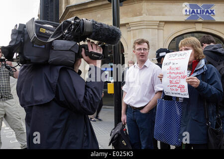 BATH, Großbritannien, 29. April 2014. Eine weibliche anti UKIP Demonstrant wird von einem Fernsehteam gefilmt, wie sie hält ein Anti UKIP-Plakat außerhalb des Forums, den Veranstaltungsort in Bath, Nigel Farage der Anführer der UK Independence Party wurde in der öffentlichen Sitzung sprechen. Bildnachweis: Lynchpics/Alamy Live-Nachrichten Stockfoto