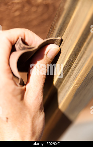 Hände einer Frau mit Sandpapier tun DIY arbeiten auf hölzernen Befestigungen Stockfoto