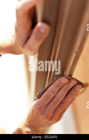 Hände einer Frau mit Sandpapier tun DIY arbeiten auf hölzernen Befestigungen Stockfoto