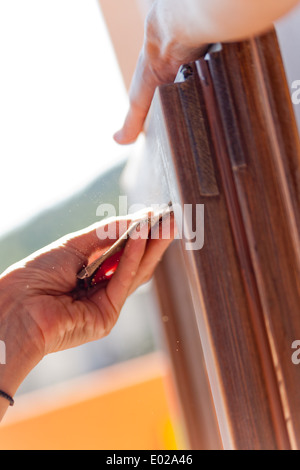 Hände einer Frau mit Sandpapier tun DIY arbeiten auf hölzernen Befestigungen Stockfoto