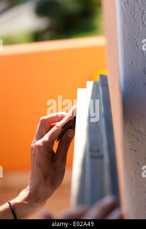 Hände einer Frau mit Sandpapier tun DIY arbeiten auf hölzernen Befestigungen Stockfoto