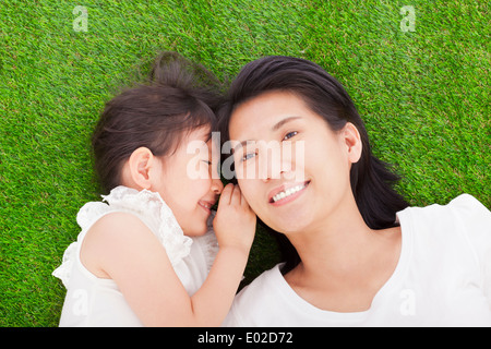 Mutter und Tochter Flüstern Klatsch auf dem Rasen Stockfoto