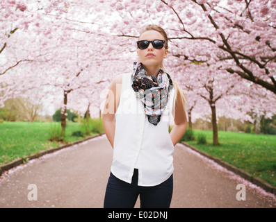 Modische junge Dame posieren selbstbewusst im Park. Attraktives weibliches Modell im Frühjahr blühen park Stockfoto